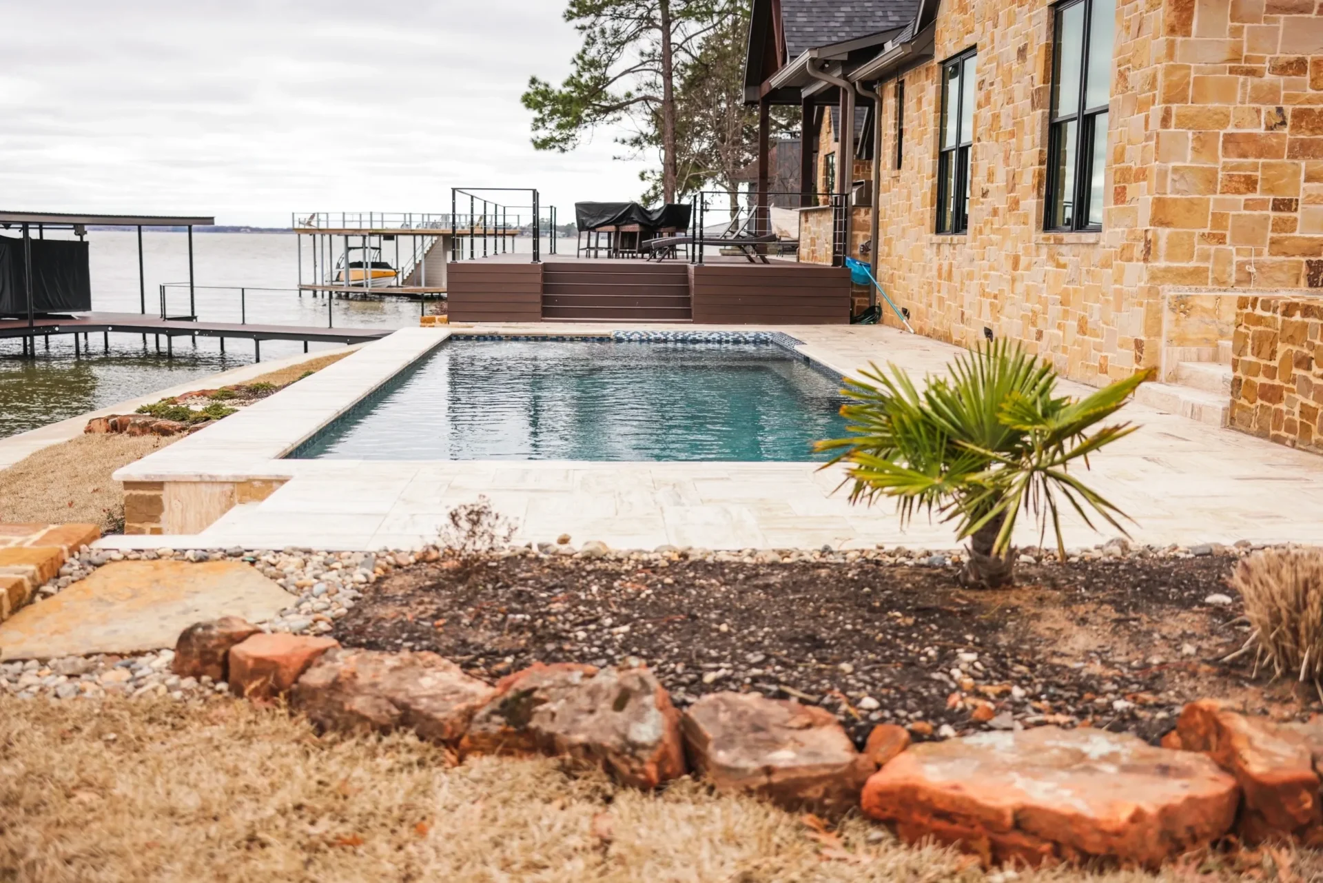 A pool with a view of the water and a palm tree.