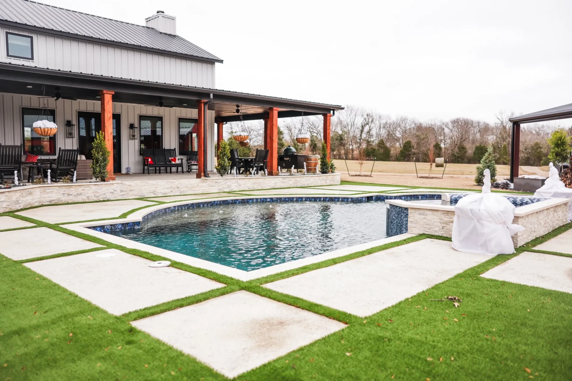 A pool with grass around it and a house in the background.